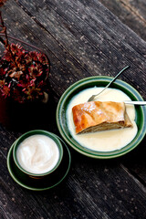 Typical Bavarian dessert apple strudel with vanilla cream on a wooden table, top view.
