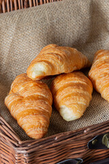 Freshly baked croissants in a wicker basket lined with hessian fabric
