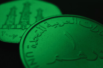 Translation: 1 one dirham United Arab Emirates. UAE coins close up. Currency of  Emirates. Dark green tinted money background. News about UAE dirham. AED. Banking and credit. Wages and taxes. Macro