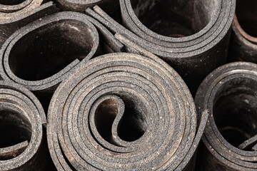 Old sheet rubber of black color, twisted into rolls, top view. rubber waste.