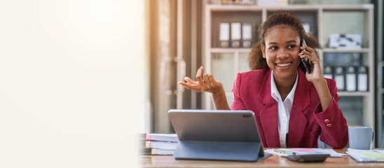 Young african american businesswoman red suit working at desk and using mobile smartphone in the...