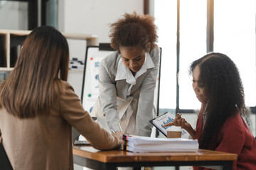 Young diverse african american female coworkers working together on start up project. Business people meeting around a boardroom table discussing creative concept