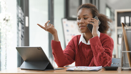 Smiling African American Hispanic student looking up from laptop at campus library, using tablet and mobile