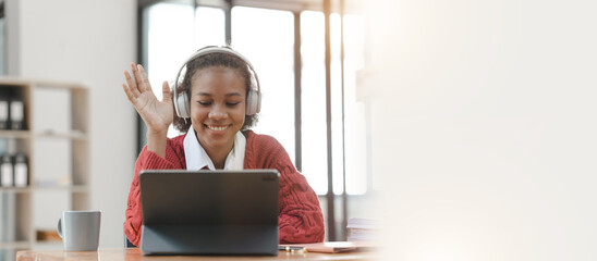Smiling African American Hispanic student looking up from laptop at campus library, using tablet and mobile