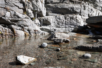 Crystal clear tiny pond left by alpine Lillaz waterfall (Cascate di Lillaz).water surrounded by granite rocks, Cogne, Aosta valley, Italy 