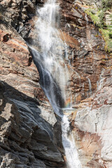 View of flowing Lillaz waterfall (Cascate di Lillaz) on&nbsp; granite karst rocks with evergreen vegetation. Aosta Valley, Italy (vertical shot)