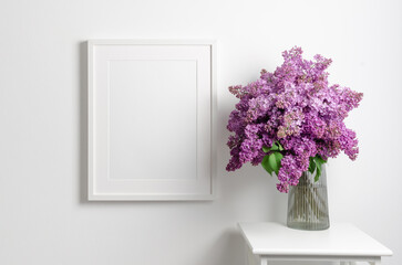 White blank picture frame mockup on wall with fresh lilac flowers bouquet, mockup with copy space