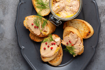 Bread or baguette toast with foie gras pate, directly above. A specialty food product made of the liver of a duck or goose,  in a glass jar. Decorated with red pepper and dill. - obrazy, fototapety, plakaty