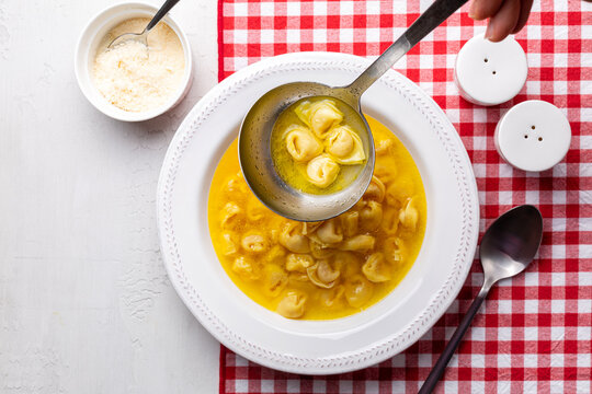 Ladle with tortellini in beef and chicken broth. Serving egg pasta originally from the Italian region of Emilia, Bologna. Stuffed with a mix of meat, prosciutto, mortadella, hard cheese, egg 