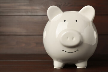 Ceramic piggy bank on wooden table, closeup. Space for text