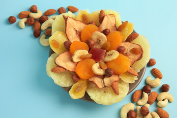 Mixed dried fruits and nuts on light blue background, closeup