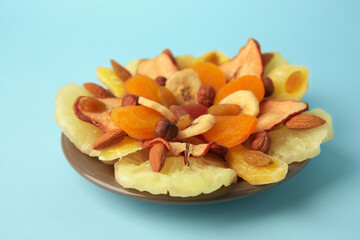 Mixed dried fruits and nuts on light blue background, closeup