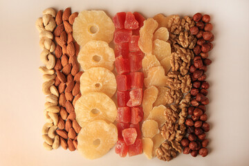 Different tasty nuts and dried fruits on beige background, flat lay