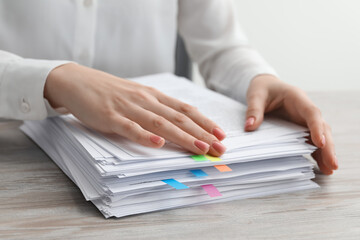 Fototapeta na wymiar Woman stacking documents at wooden table in office, closeup