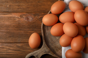 Raw brown chicken eggs on wooden table, flat lay. Space for text