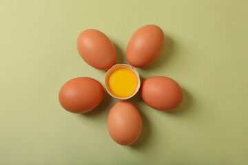 Flower made with cracked and whole chicken eggs on olive background, flat lay