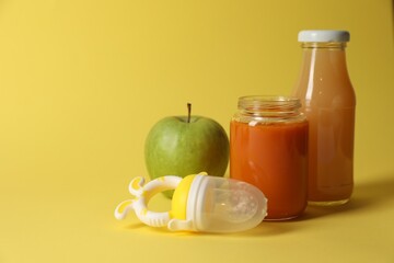 Healthy baby food, apple, juice and nibbler on yellow background, space for text