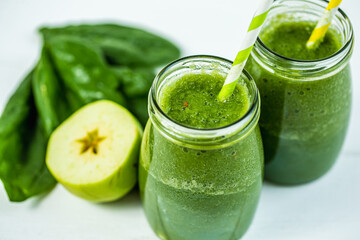 From above view of glasses jars with straws filled with green smoothie and ingredients on the table