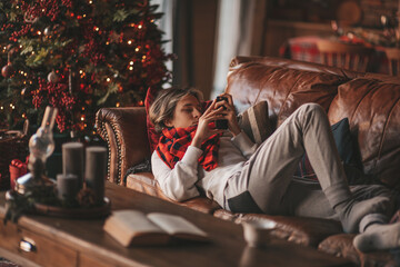 Portrait of candid authentic smiling handsome boy teenager using mobile phone at Xmas home interior