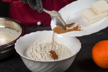 Human hands adding cinnamon to ingredients for making cookies