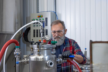 Mature man in protective eyeglasses working on a factory equipment