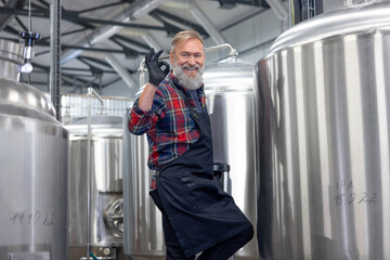 Factory worker checking the tanks with beer and looking satisfied with the result