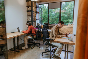 Young businessmen working in coworking office sitting at tables