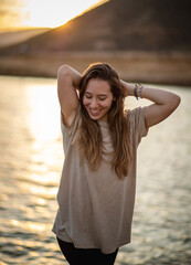 Young girl in the sunset at the seaside smiling at the camera with the ocean behind