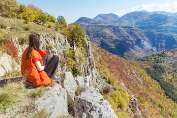 Naklejka premium Traveler Woman sitting on a rocks in the autumn mountain . Balkan mountains, ,Bulgaria
