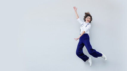 Fototapeta na wymiar attractive asian lady jumping high up rejoicing wear white shirt and blue jumper white sneaker shoes on isolated background with copy space for advertising banner.
