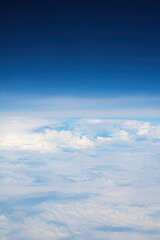 White cumulus clouds seen from the passenger airplane on sunny summer day, aerial view
