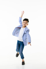A 10-year-old Asian boy in a casual jacket is jumping smartly and happily looking at the camera against a white isolate background. - 557931137