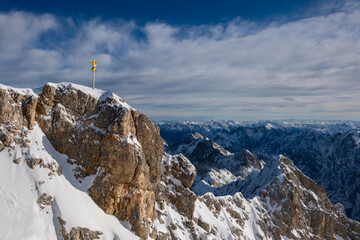 “Zugspitze“ peak with golden summit cross is the hightest mountain top in Germany on the border to Austria. Winter panorama above Garmisch-Partenkirchen with alpine scenery on a sunny december day.