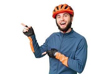 Young cyclist man over isolated chroma key background surprised and pointing side - obrazy, fototapety, plakaty