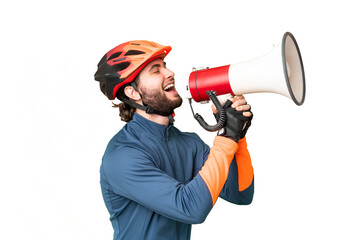 Young cyclist man over isolated chroma key background shouting through a megaphone - obrazy, fototapety, plakaty