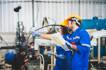 Engineers team mechanic using computer controller Robotic arm for welding steel in steel factory...