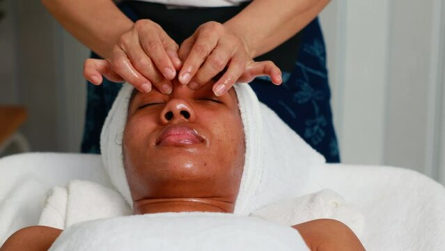 facial treatment. Beautiful African American woman getting face massage in beauty spa and wellness center. Facial treatment and skin care concept.