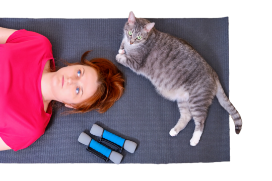 A tired woman and a cat lie on a training mat after a sports workout, isolated on a white background. Concept of isolation during the coronavirus epidemic and sports training - Powered by Adobe