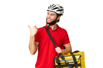 Young delivery man with thermal backpack over isolated chroma key background pointing to the side to present a product