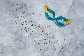 Carnival mask and varicolored glitter confetti. Top view, Close up on  marble background.