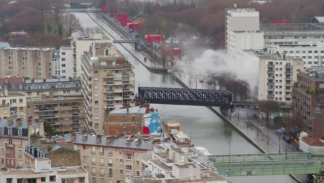 Vue a&eacute;rienne de panaches de vapeur qui s''&eacute;chappent d'un b&acirc;timent urbain au bord du canal de l'Ourcq &agrave; Paris