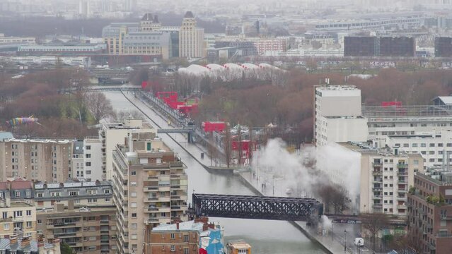 Vue a&eacute;rienne de panaches de vapeur qui s''&eacute;chappent d'un b&acirc;timent urbain au bord du canal de l'Ourcq avec au loin le p&eacute;riph&eacute;rique.