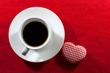 Set of coffee cups with heart shape made of red-white checkered fabric laying on red velvet floor, flat lay, space for text, Valentine's day concept.