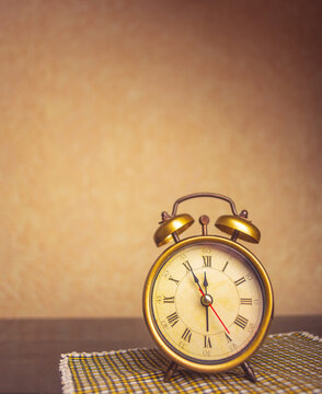 Retro alarm clock with five minutes to twelve o'clock. Old style filtered photo