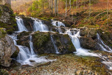 Fototapeta na wymiar Wasserfall Kaskade im Wald mit rötlichem Herbstlaub