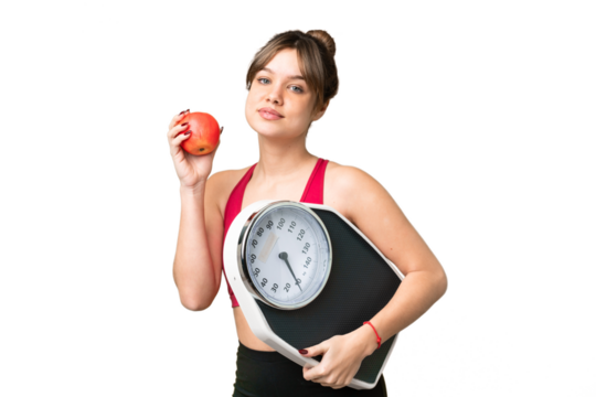 Young girl over isolated chroma key background with weighing machine and with an apple
