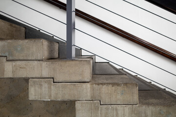 Selective focus at raw concrete riser and tread, and metal railing, loft and brutalist architecture...
