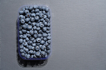 Ripe blueberries in plastic box on stone table