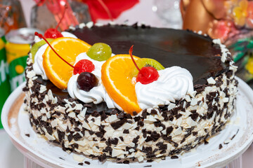 A delicious and beautiful cake decorated with cherries, kiwi and orange.