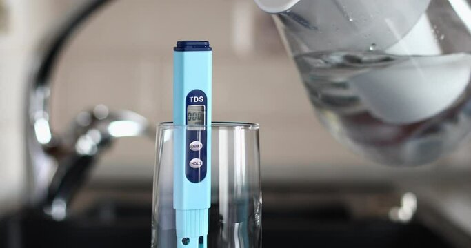 A person takes a filter with water and pours it into a glass with a tds meter to check the water quality. The concept of checking the suitability of water for drinking